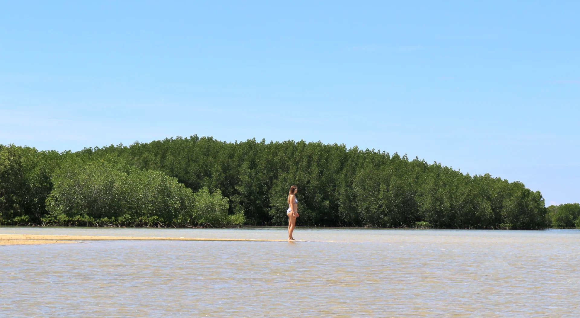 Deanna standing on a thin sliver of sand surrounded by water on the disappearing Luli island