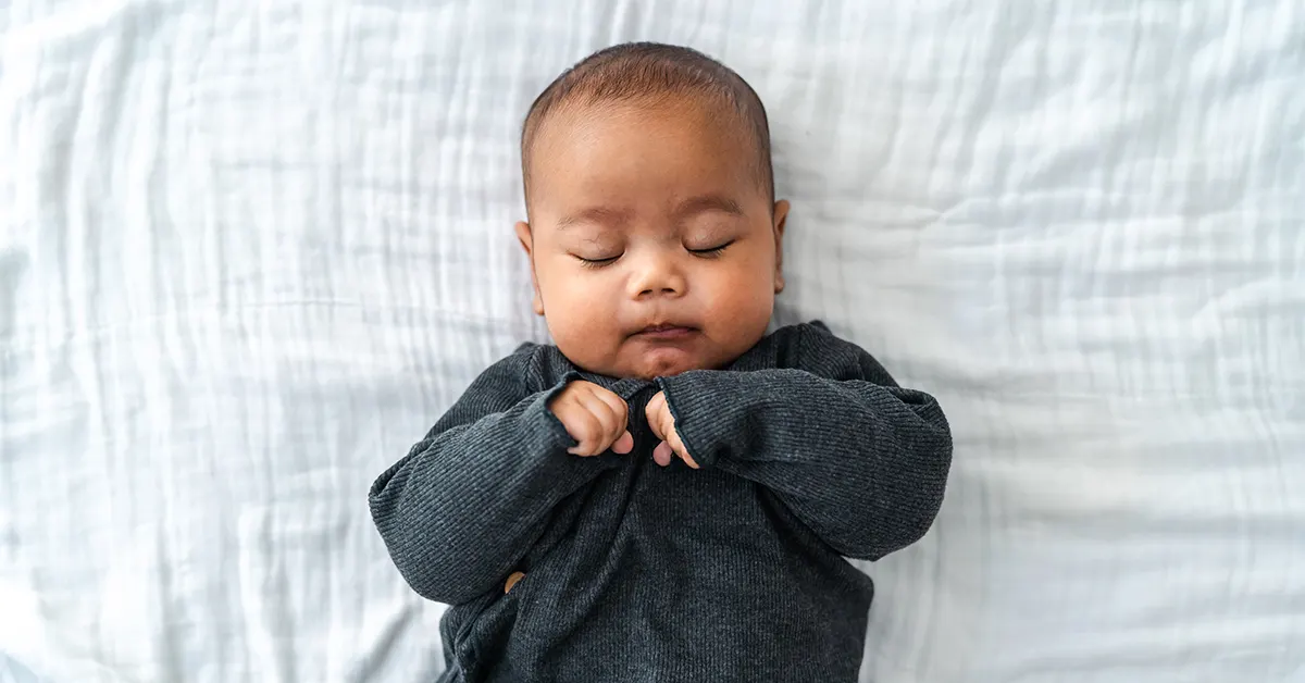 Bébé endormi paisiblement, représentant l'importance d'un bon sommeil pour gérer l'énurésie nocturne chez les enfants