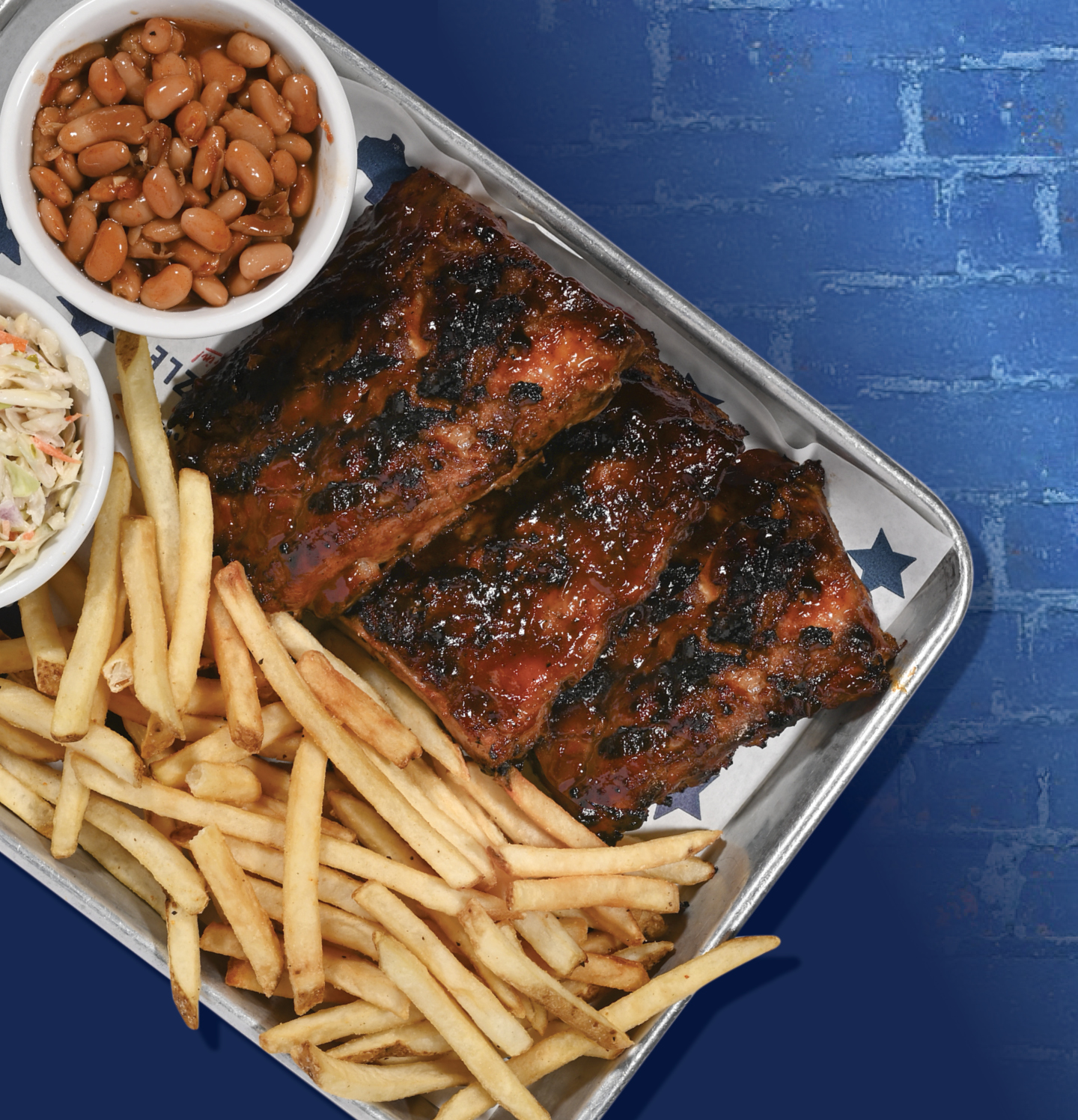 Platter of ribs with a side of fries, coleslaw and baked beans. 