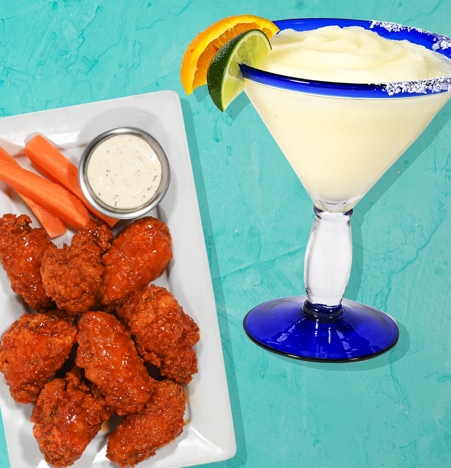 Plate with chicken wings, carrots and dip. Margarita with lime and salt rim. 