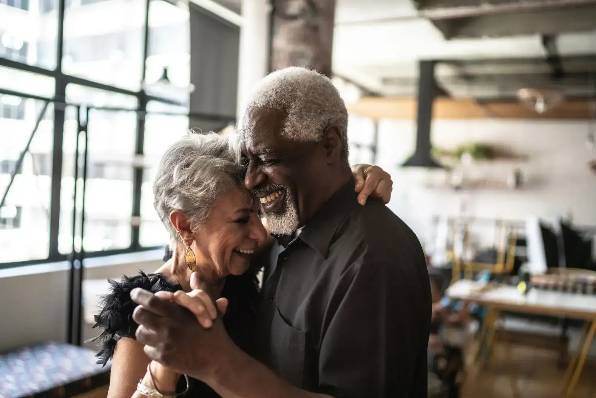 An elderly couple sharing a dance in home, radiating happiness in a charming and intimate setting