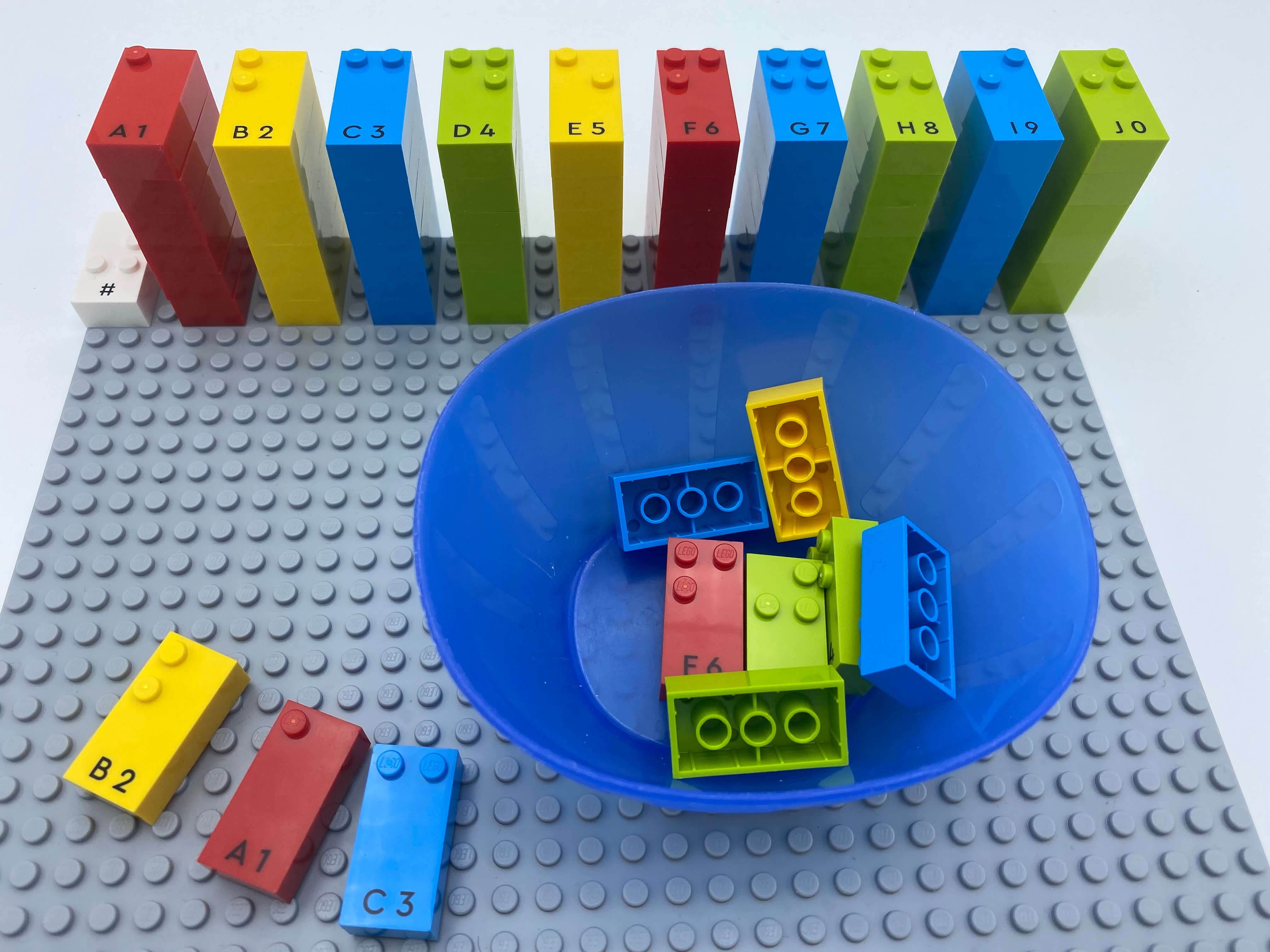 Numbers sign brick and 10 towers of number bricks aligned on the base plate. a bowl with bricks and 3 number bricks out of the bowl: 2, 1, 3.
