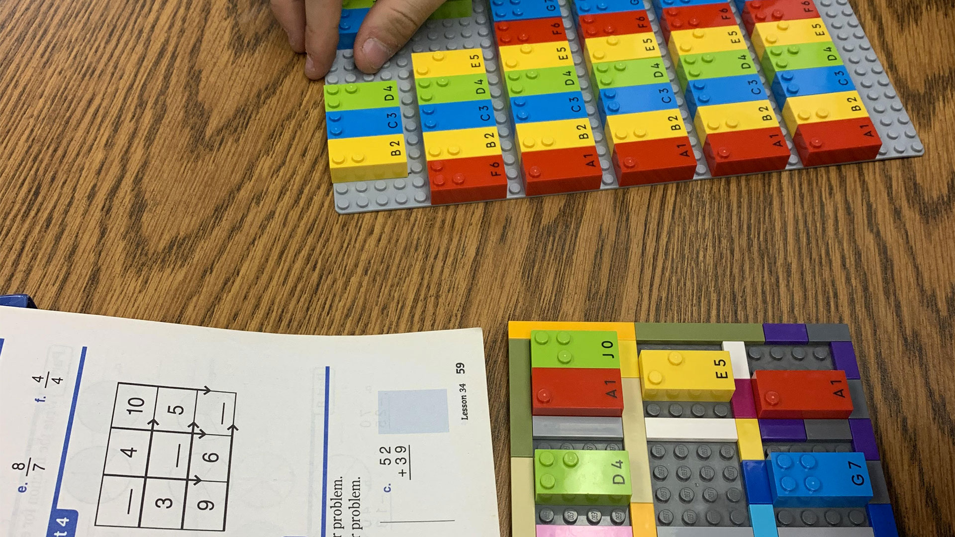 To solve an addition problem, a blind student uses a LEGO grid and LEGO Braille Bricks instead of a paper braille version.