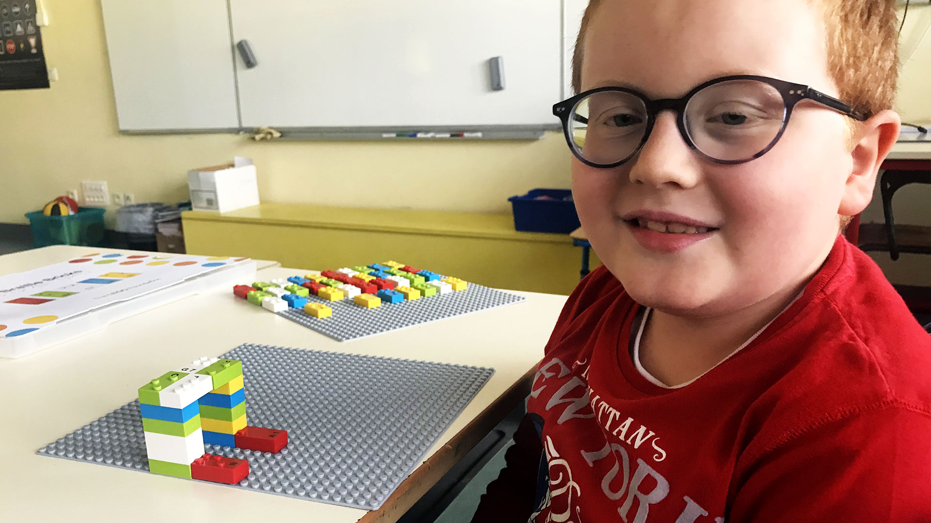 A young boy with LEGO Braille Bricks and a baseplate, doing a pre-braille activity.