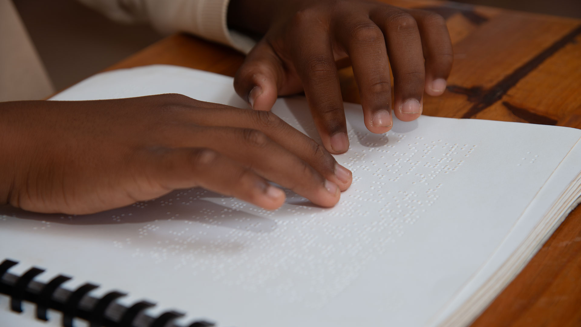 Child's hands reading a document in braille.