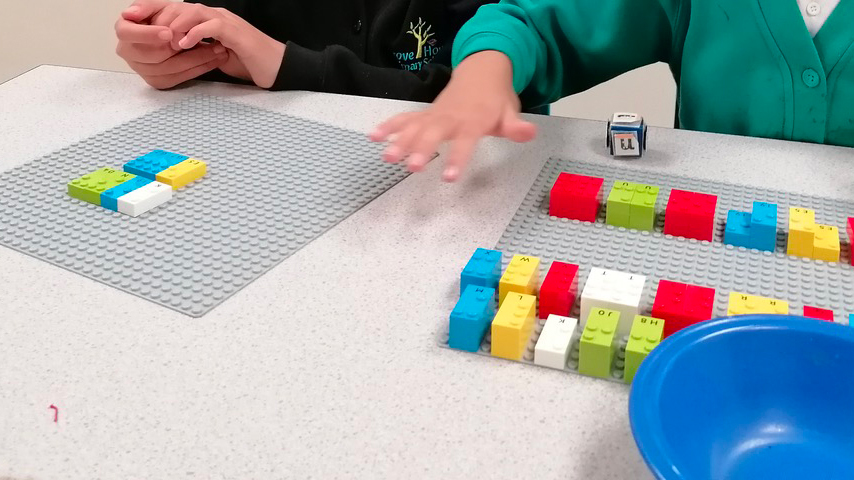 Girl throwing dice to play vowels with LEGO Braille Bricks