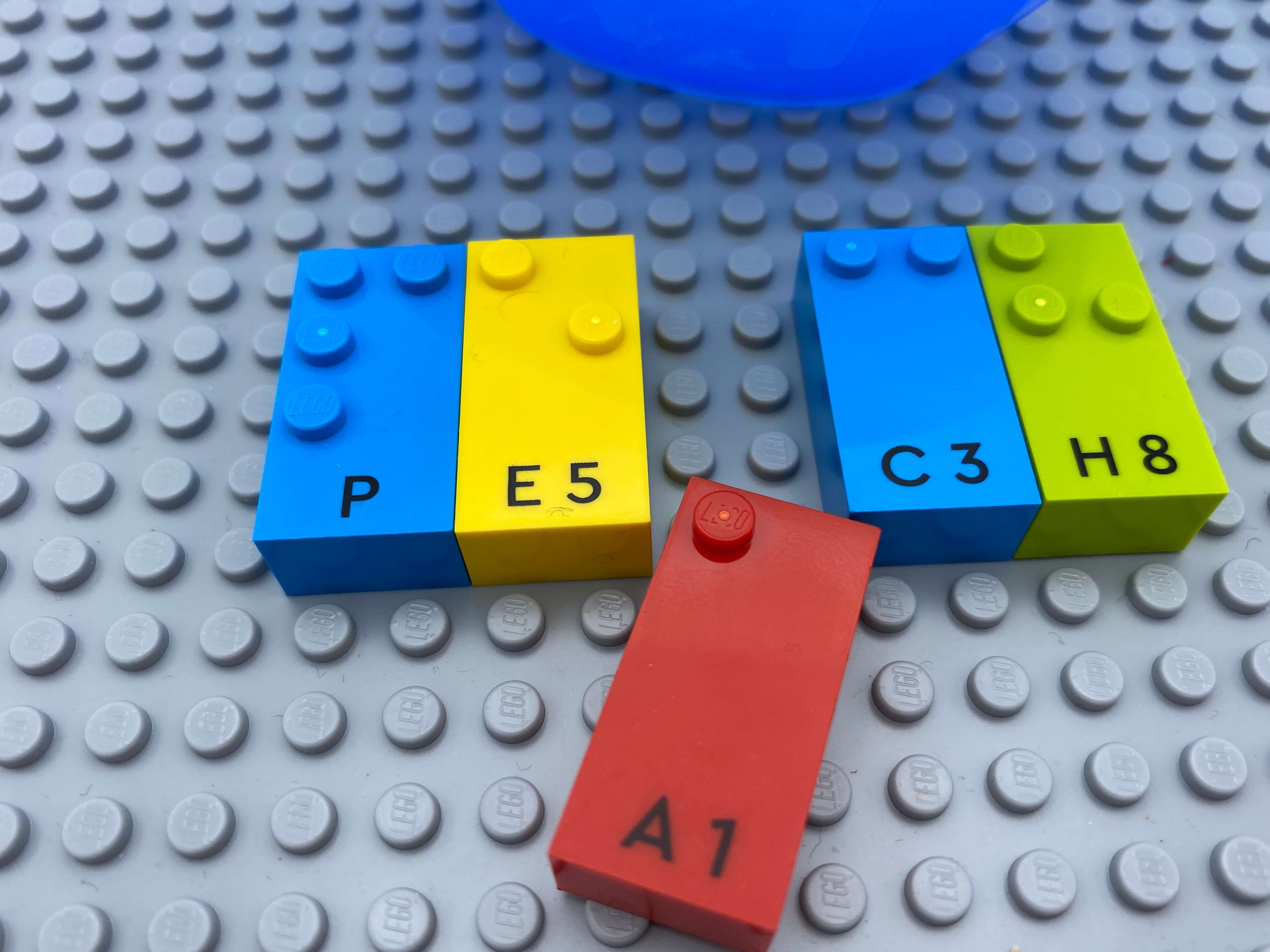 2 pairs of letter bricks (p, e and c, h) aligned on the base plate, a letter brick a in between is being removed.