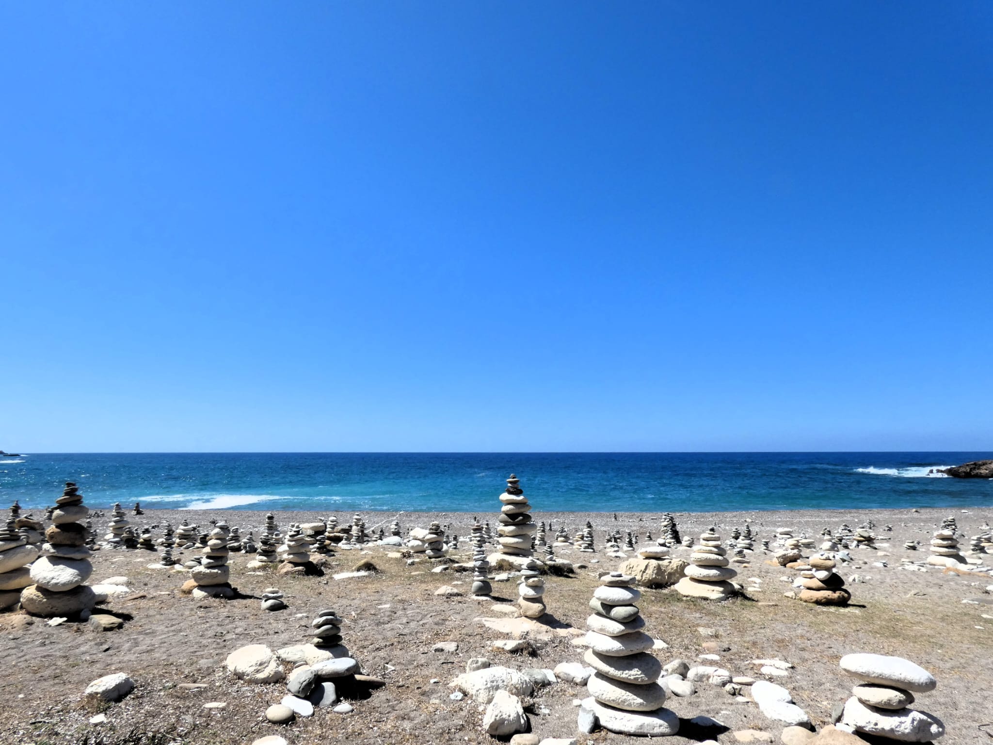 Piccole rocce ammucchiate in gruppi in una spiaggia, di fronte al mare