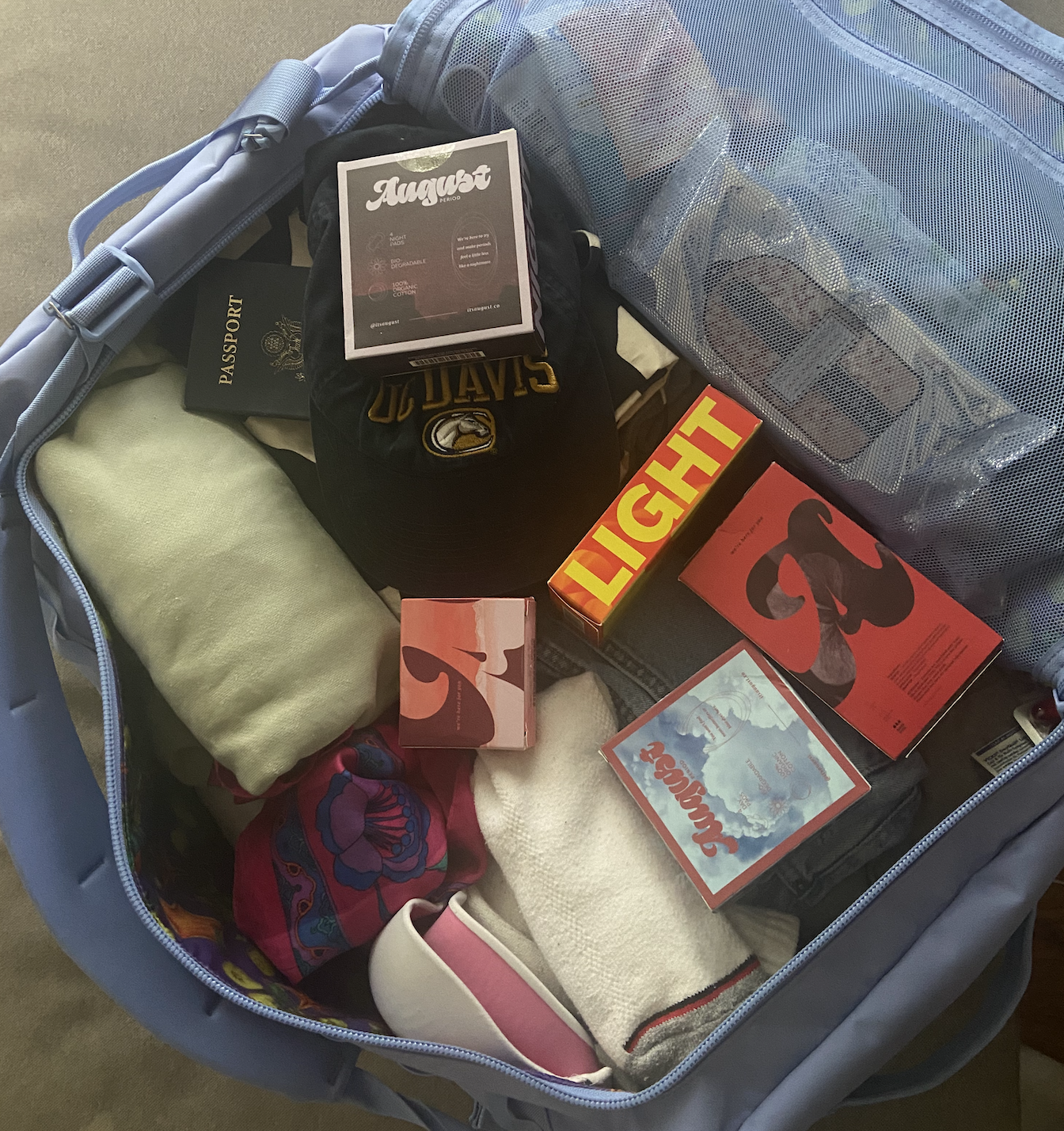 An open suitcase filled with august period product boxes and clothes