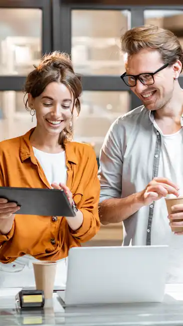 Woman and smiling while she shows a man something on her tablet