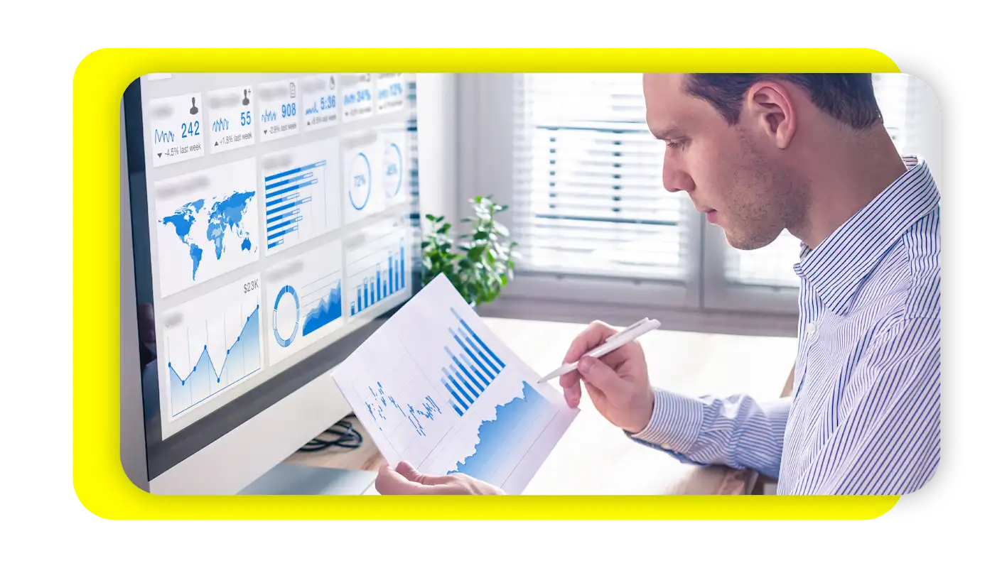 Man looking at graphs on paper and iMac.