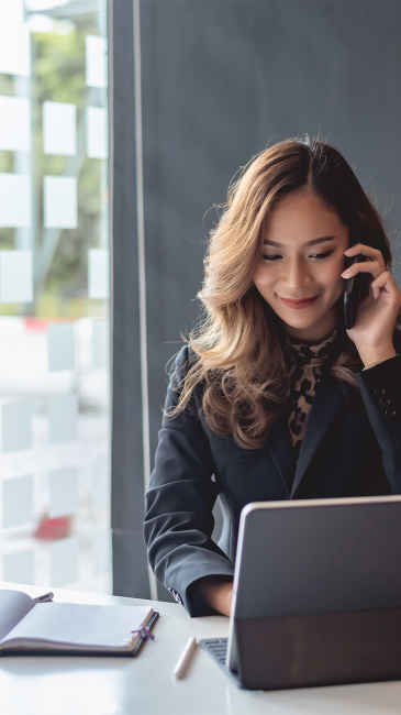 Woman looking at her laptop while listening on her mobile phone