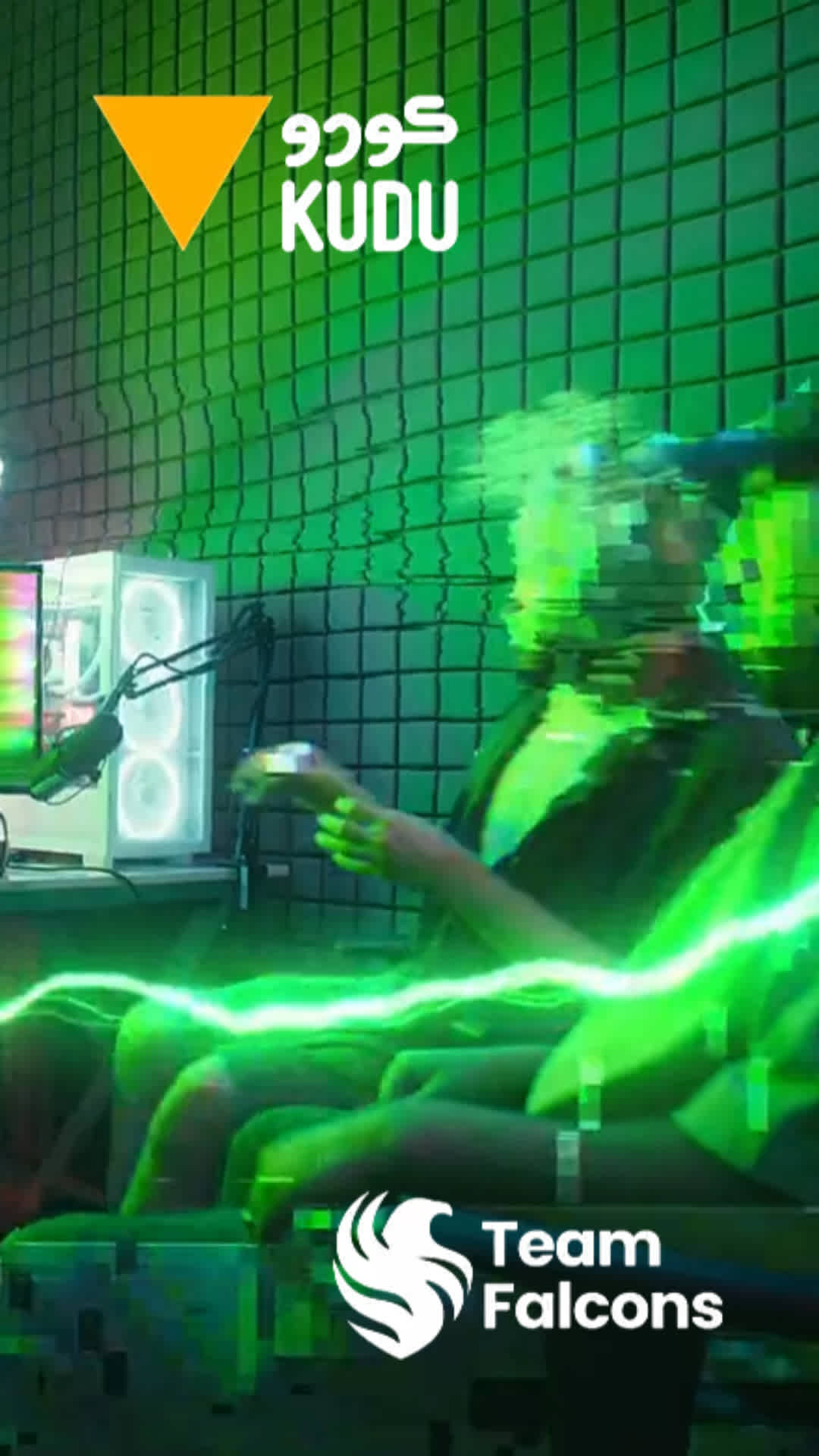 A person streaming in a green-lit room with ‘KUDU’ in English and Arabic, an orange triangle, and ‘Team Falcons’ logo.