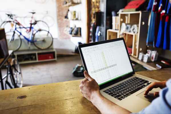 Homme dans une boutique de vélo utilisant une feuille de calcul sur son ordinateur portable