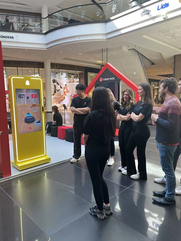 Group viewing Roborock game on Snapchat AR kiosk during brand activation.