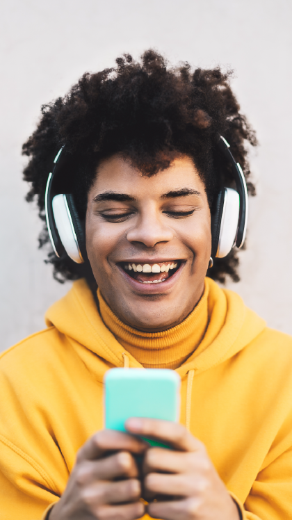 Man with headphones on looking at his mobile phone and smiling