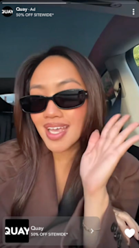 Creator wearing black sunglasses records selfie style video in car promoting Quay sale in vertical video advertising.
