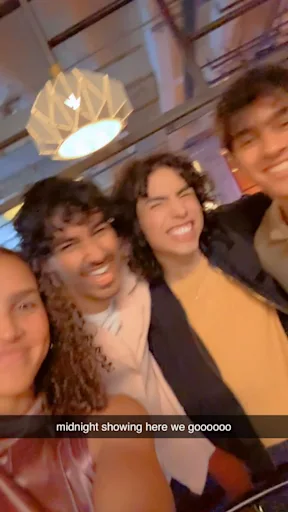 Group of friends smiling at a midnight movie showing, highlighting social excitement that drives cinema attendance.