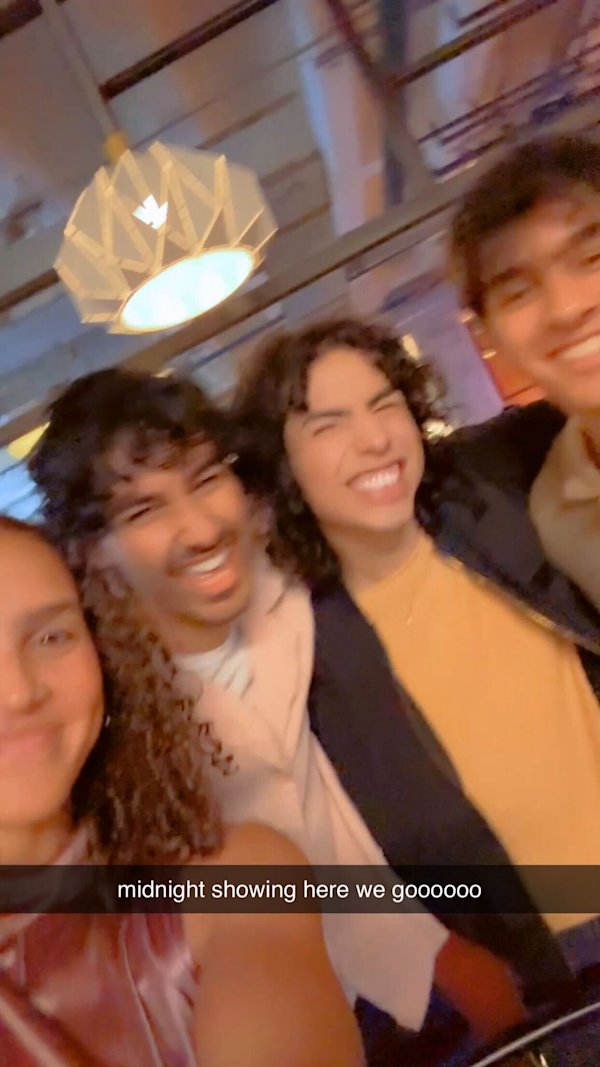 Group of friends smiling at a midnight movie showing, highlighting social excitement that drives cinema attendance.