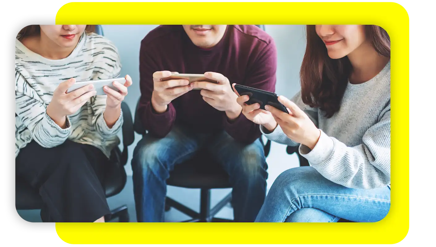 Two women and a man all smiling while looking at their own mobile phones