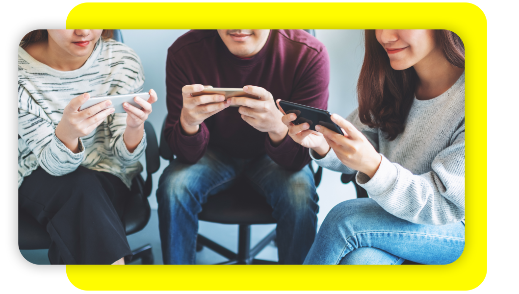 Two women and a man all smiling while looking at their own mobile phones