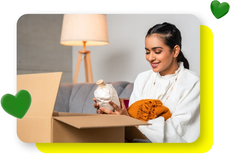 Smiling Saudi woman unboxing an online purchase, with floating heart emojis overlaid
