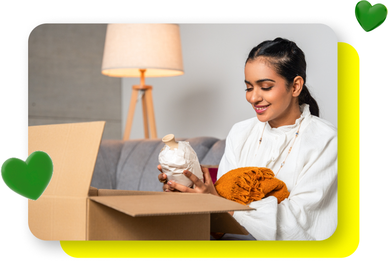 Smiling Saudi woman unboxing an online purchase, with floating heart emojis overlaid
