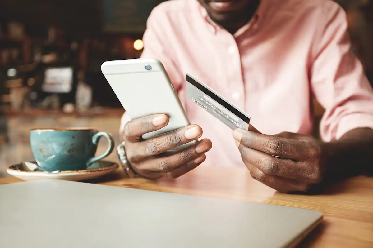Person using a smartphone while holding a credit card, representing Snapchat Ads pricing and mobile advertising costs.