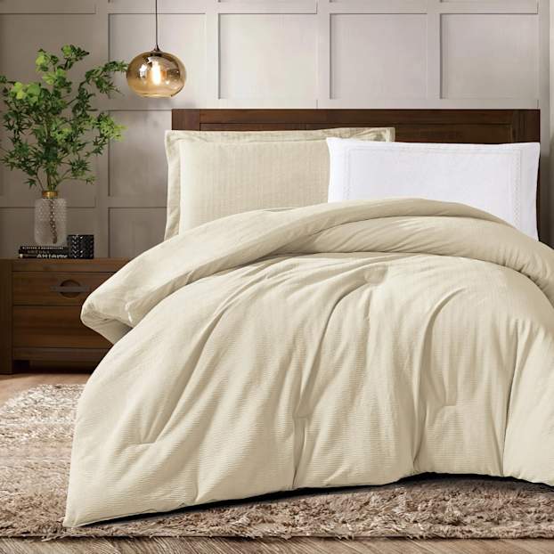 غرفة نوم دافئة بفرش بلون محايد واضاءة هادئة تعرض ضمن قصة نجاح لعلامة منزلية.