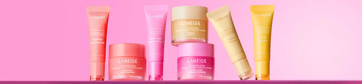 Colorful Laneige lip balms and sleeping masks in grapefruit, sweet candy, vanilla, and mango flavors against a pink background.