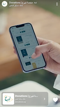 Hand holding a mobile phone, scrolling through donation options on the National Donations app.