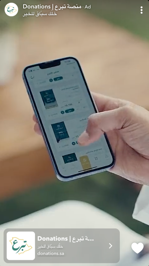 Hand holding a mobile phone, scrolling through donation options on the National Donations app.