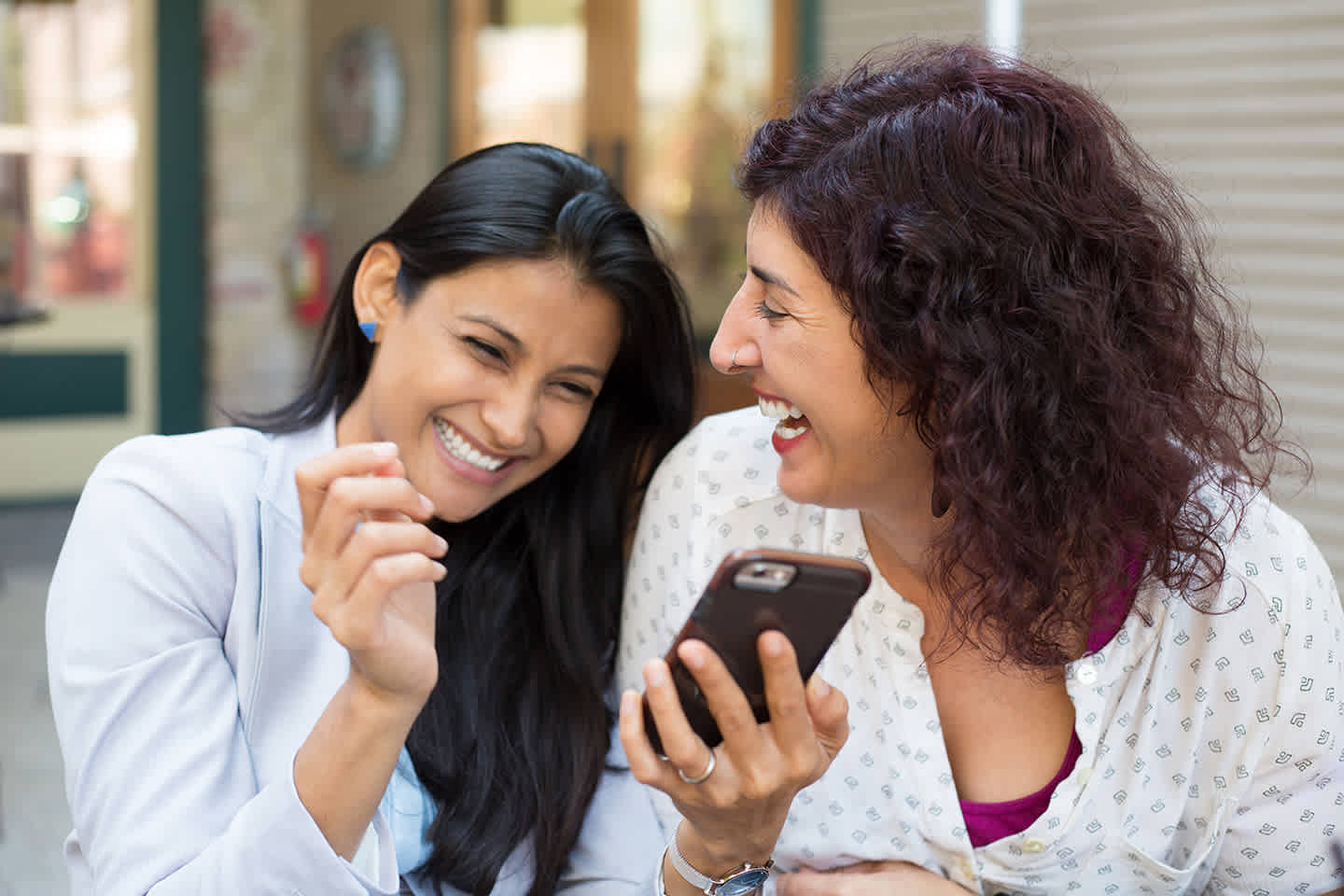 Two friends smile while scrolling phone together