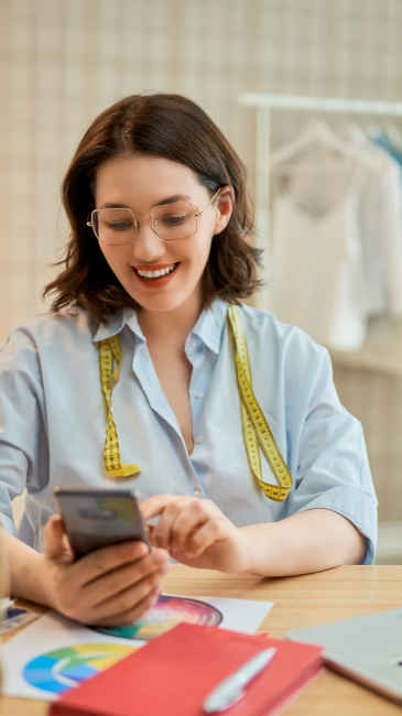 Styliste souriant et tapant sur son téléphone portable