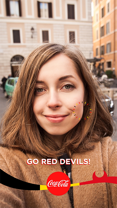 Person holding a phone using a branded Snapchat AR face filter from a Coca-Cola campaign, showing phone-based social AR in a brand activation context