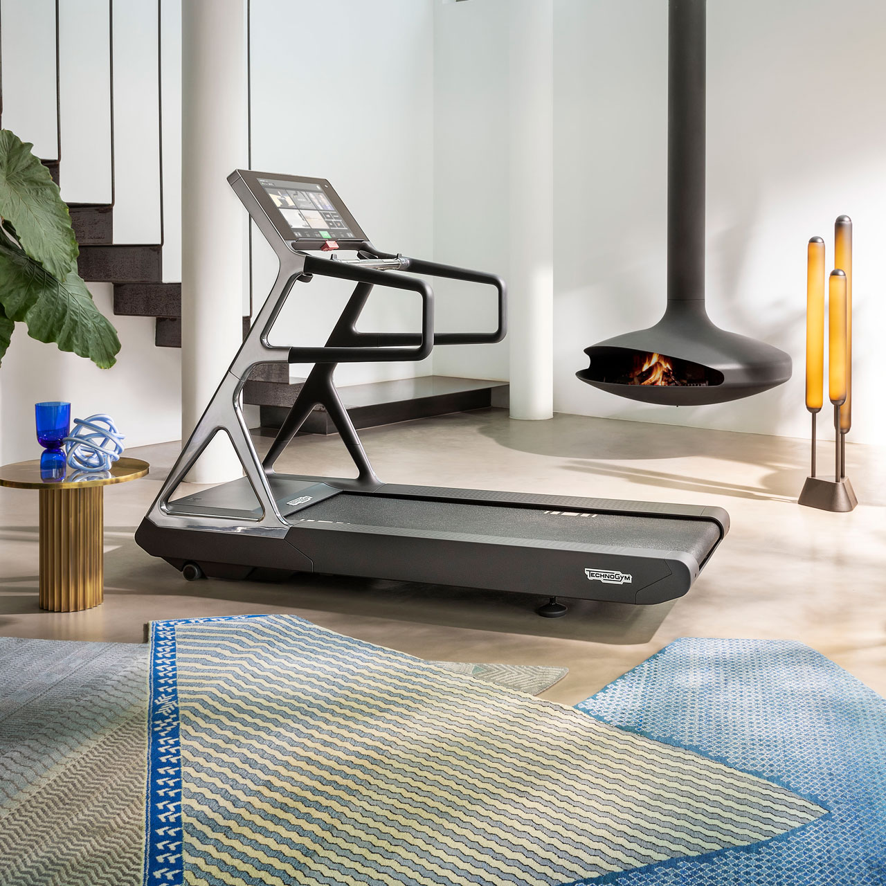 Luxury treadmill Run Personal in a designer apartment setting with light blue carpets on the foreground, a modern and minimalistic fireplace and staircase on the background