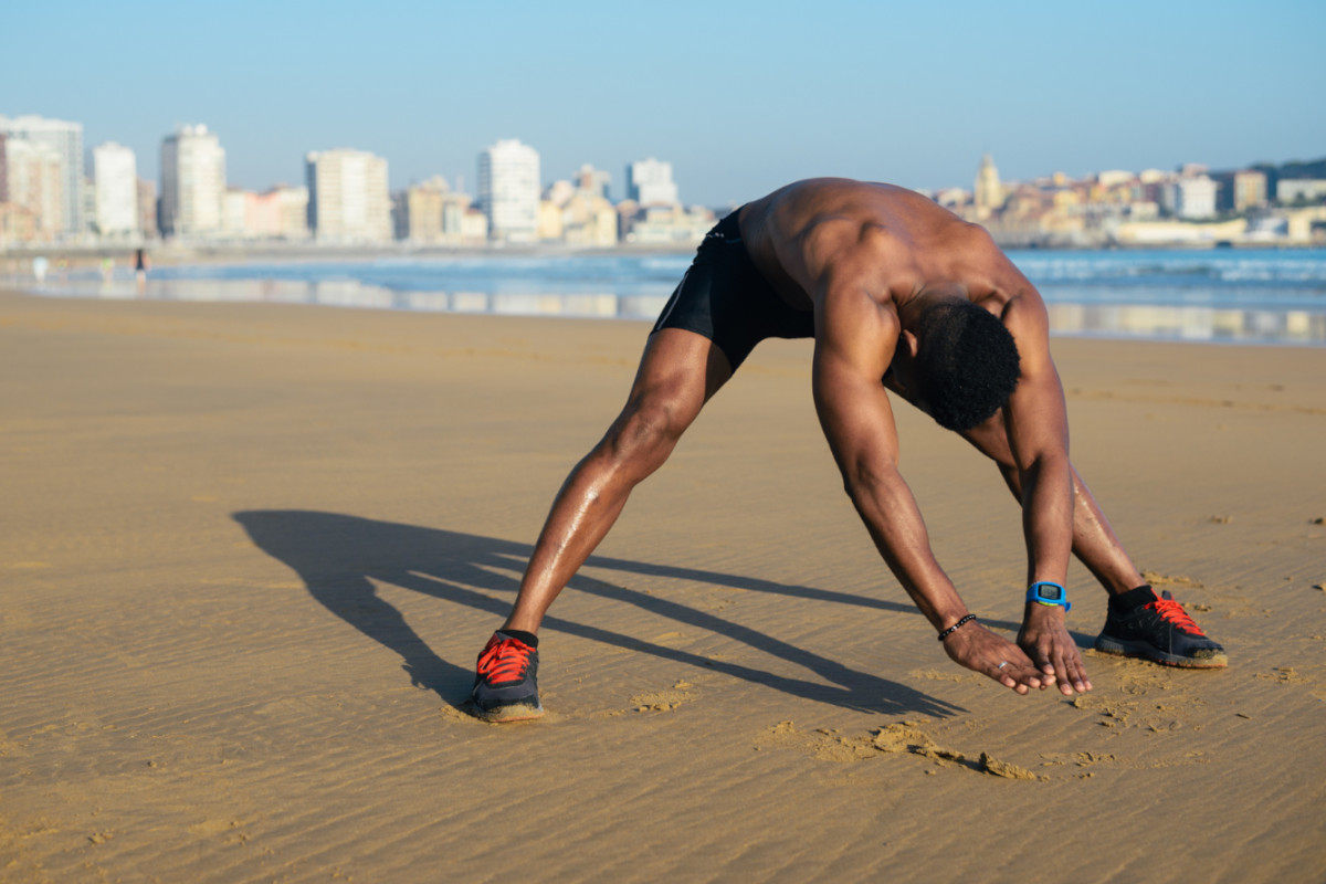 Man performing stretching on the beach after a run