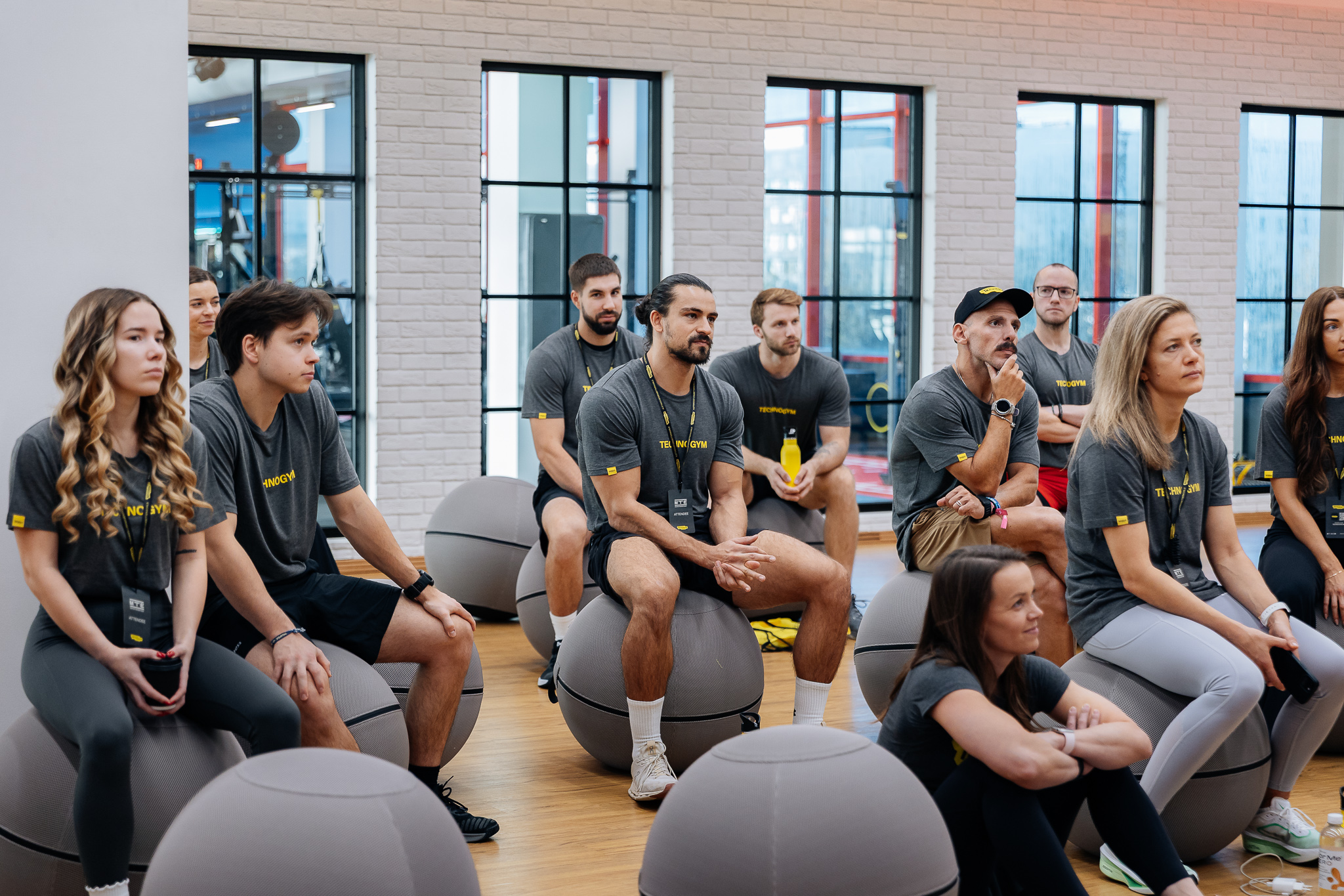 En gruppe Technogym Master Trainers under en opplæringsøkt, sittende på Wellness Ball i et moderne miljø dedikert til utdanning og faglig utvikling innen treningsbransjen.