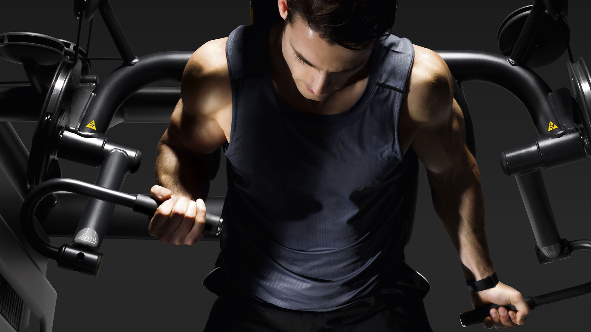 Man training on a biceps curl machine with his right arm lifting weight, while the left one rests