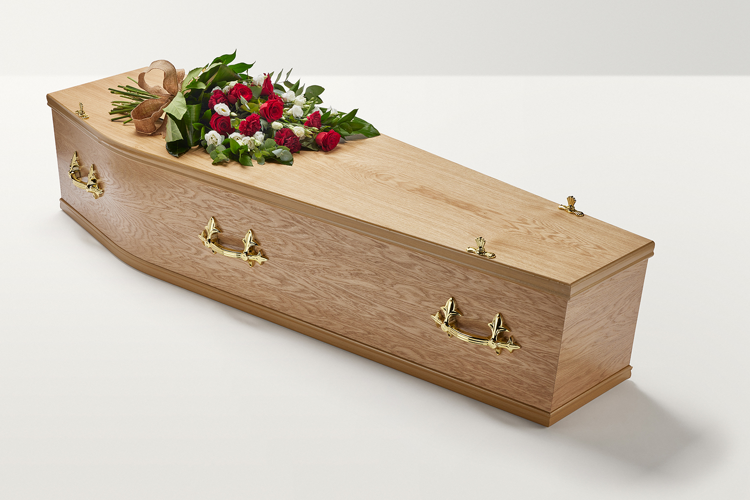 Zoomed out shot of red floral display with hand-tied bow on top of coffin