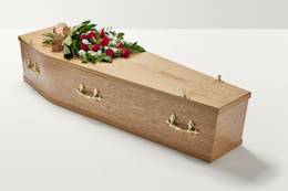Zoomed out shot of red floral display with hand-tied bow on top of coffin