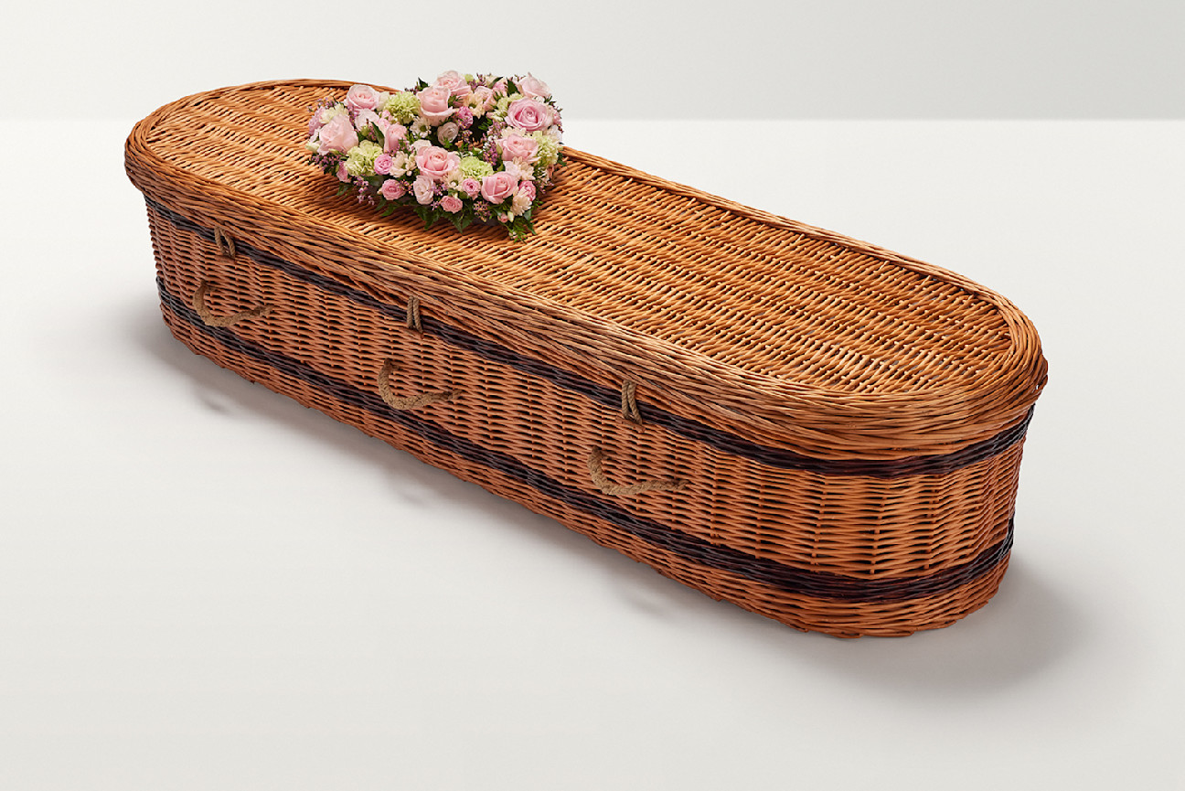 Zoomed out shot of pastel pink floral display on top of coffin