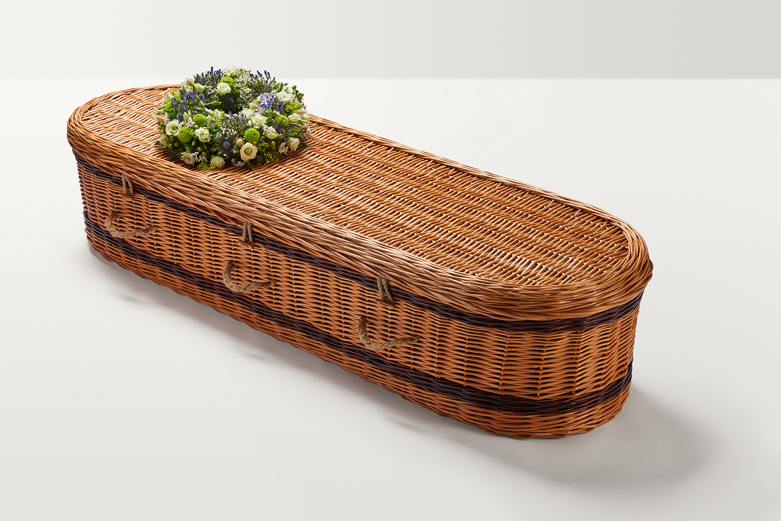 Zoomed out shot of blue and green wreath of flowers on top of coffin