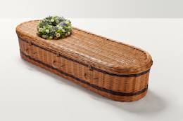 Zoomed out shot of blue and green wreath of flowers on top of coffin