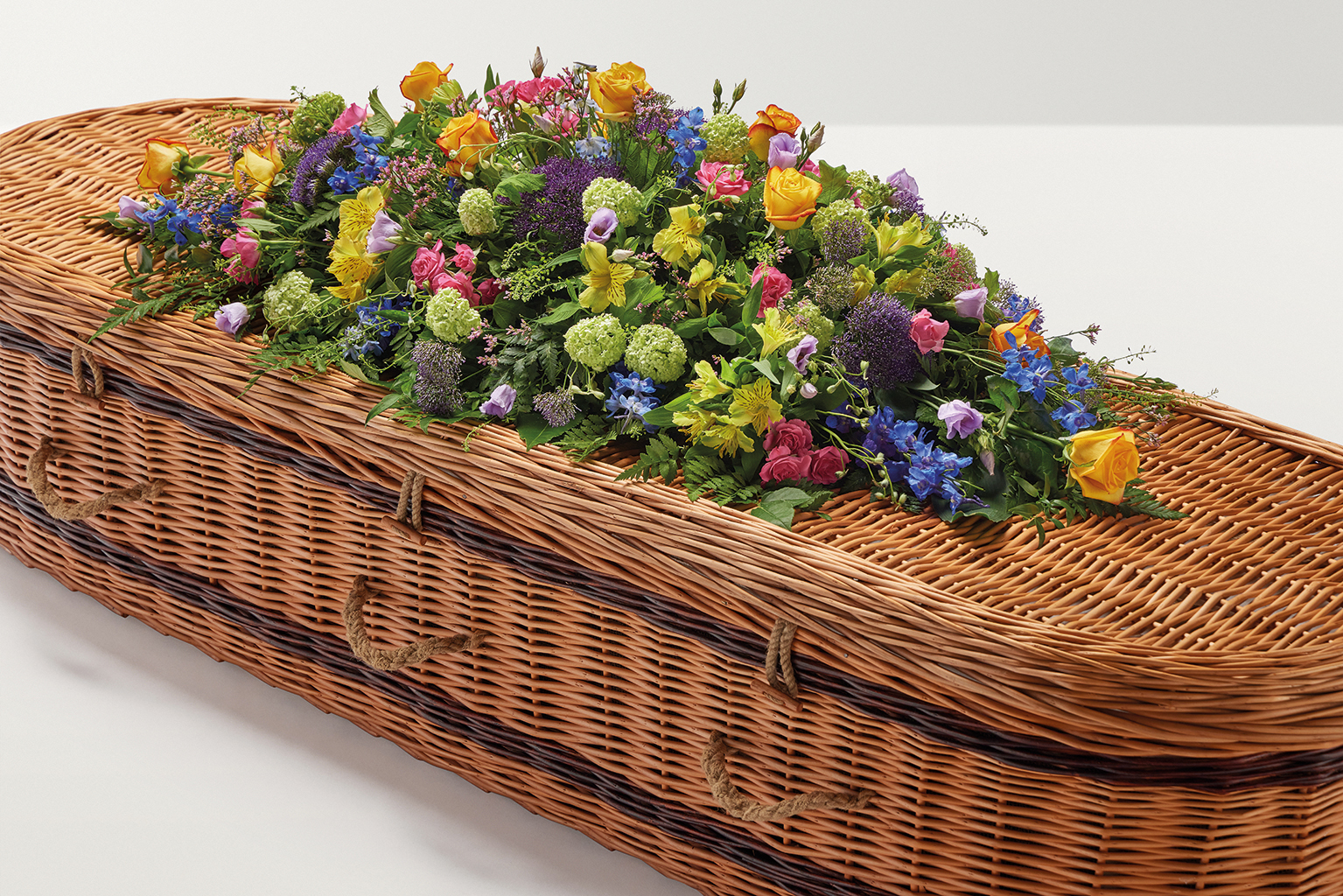 Brightly coloured country mixed coffin spray on top of coffin
