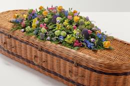 Brightly coloured country mixed coffin spray on top of coffin