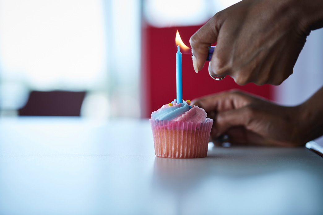 Person lighting a candle in a single cup cake. 