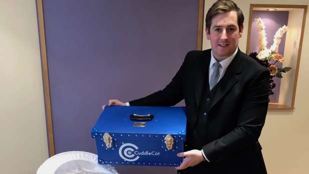 Funeral director holding a cuddle cot. 