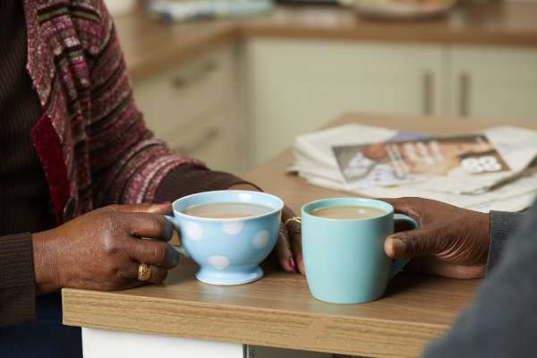 Couple chatting in their kitchen over a cup of tea. 