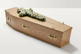 Zoomed out shot of white flowers in the shape of a cross on coffin